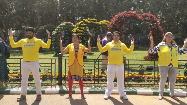 Praktykujący Falun Dafa medytują obok swojej ekspozycji i stoiska na 213. dorocznej wystawie kwiatów w Bangalore, w Indiach, podczas obchodów Dnia Republiki Indii 26 stycznia 2023 r.